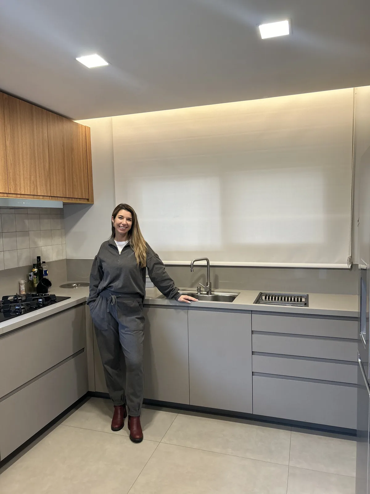 Lauren ao lado de uma cortina rolô instalada em uma cozinha
