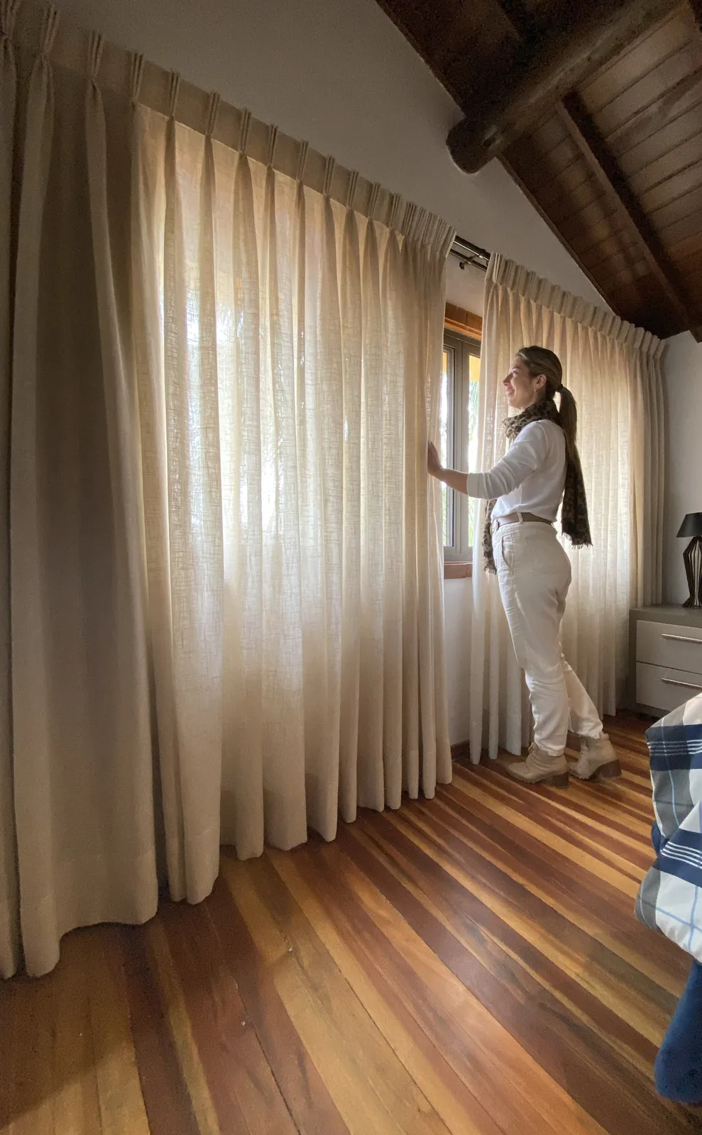 Lauren ajusta uma cortina de tecido em um quarto